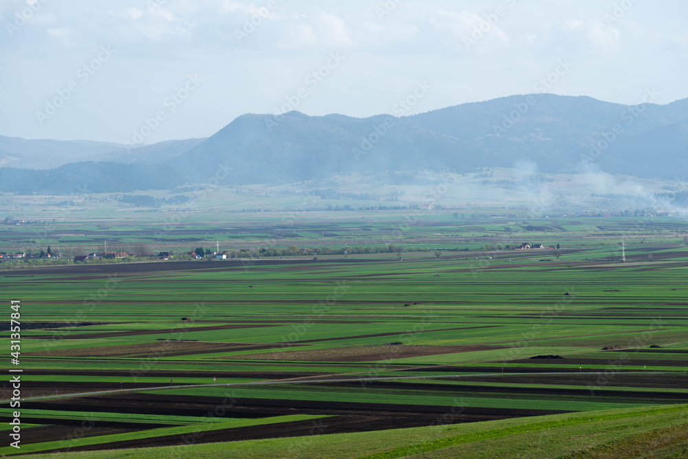 Fototapeta premium Vibrant green meadow and agricultural fields at springtime in Transylvania, Romania.