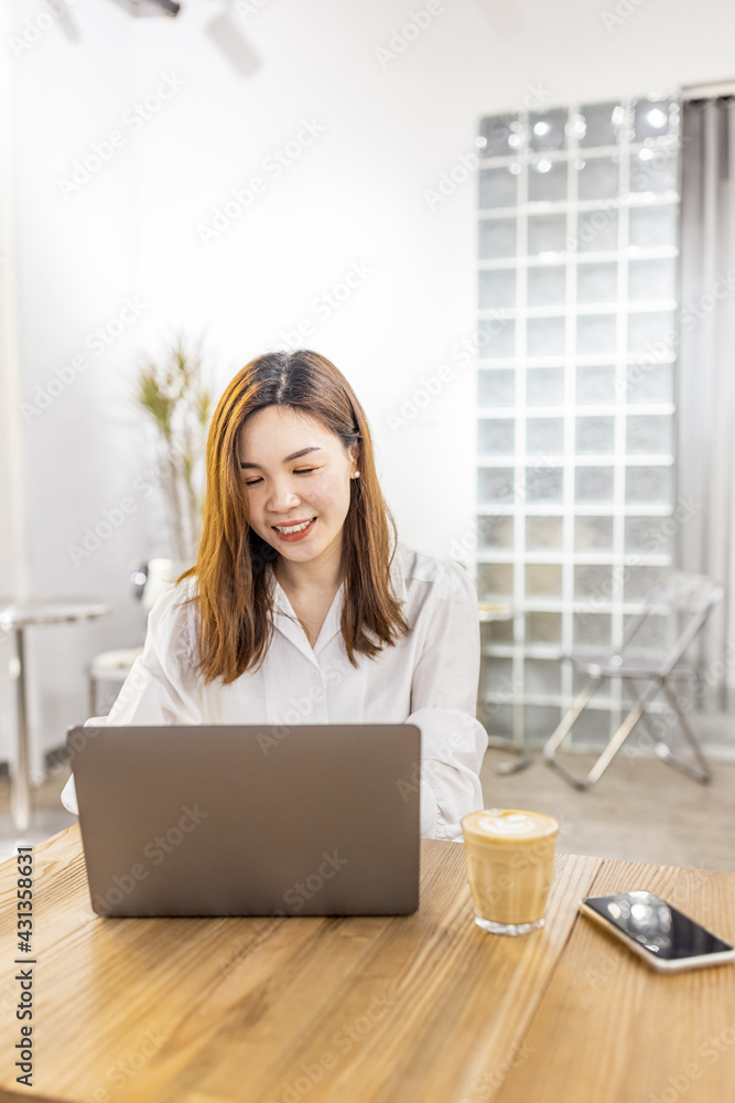 Pretty young asian business woman using laptop in modern cafe. Pretty young asian business woman using laptop in modern cafe.
