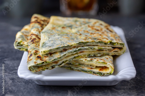 Traditional Turkish food gözleme with cheese and spinach. Turkish pancake gozleme concept on the dark background.
