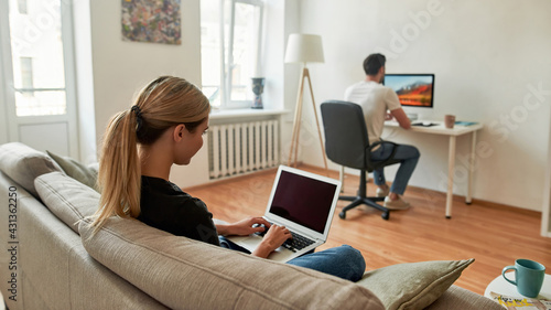 View from the back on a young couple distant working in living room