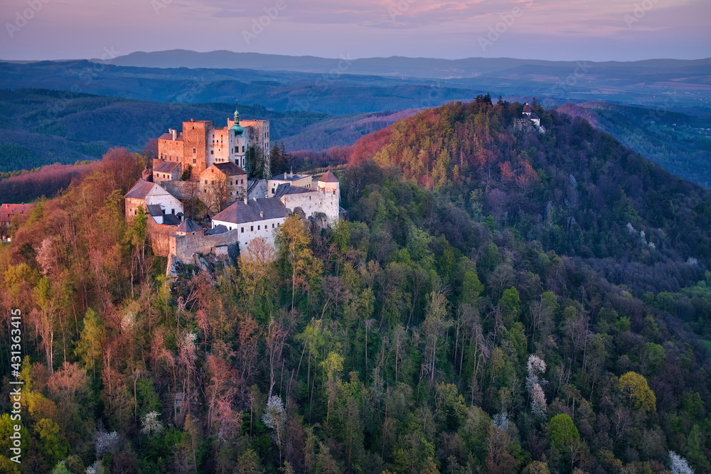 Aerial view on Buchlov Castle, one of the most important castles in Moravia. Monumental castle in Romanesque Gothic style, standing on a wooded hill, lit by reddish light of setting sun. Czech castles