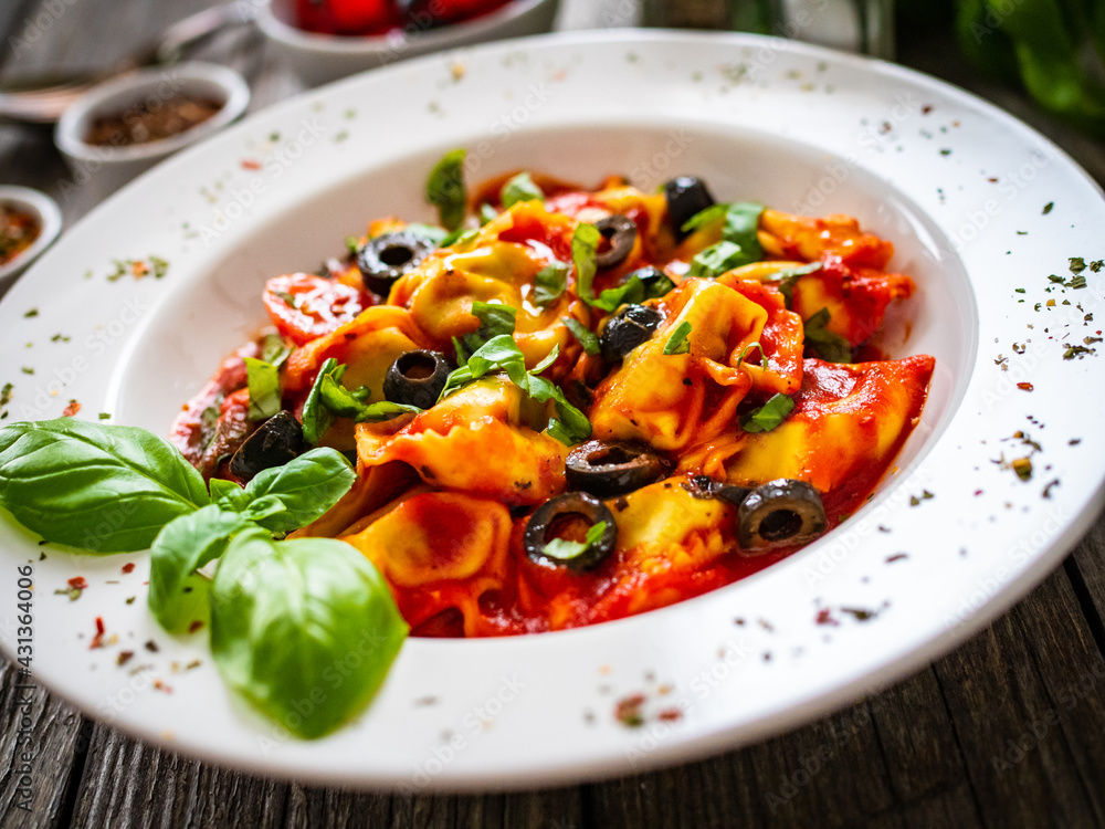 Tortelloni stuffed with prosciutto ham and vegetables on wooden table
Tortelloni stuffed with prosciutto ham and vegetables on wooden table