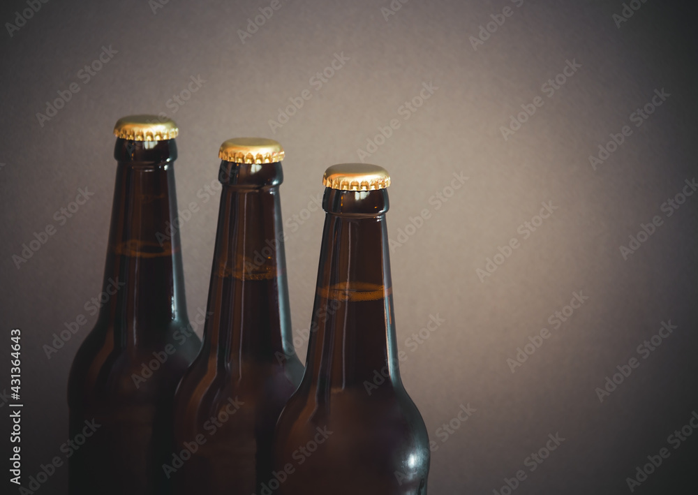 Glass bottles of beer on gray background. Selective focus.