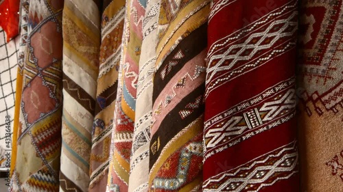 Close-Up Pan Of A Large Collection Of Carpets And Textiles Hanging On Display At A Market, With Vibrant Colors And Weaves - Casablanca, Morocco