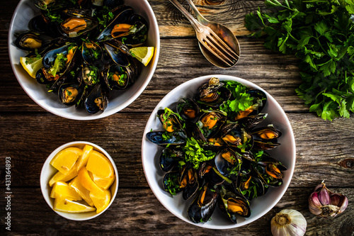 Cooked mussels with lemon and parsley on wooden table
