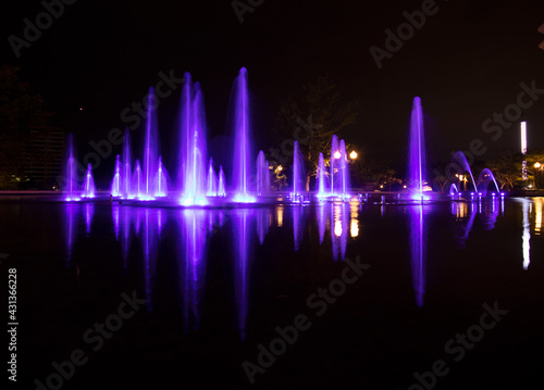 Long exposure of a colourful outdoor water fountain at night - illuminated purple fountains