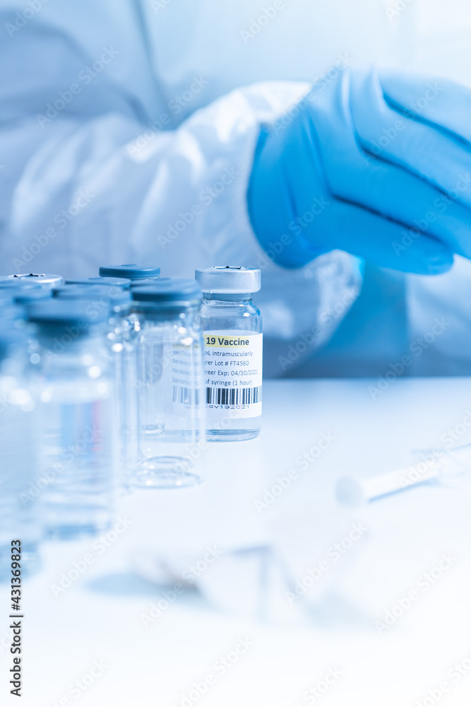 Focus on vaccine vial containing COVID 19 cure. Ready to administer the shot. Medical research against Coronavirus. Vaccine from respiratory syndrome strain of virus on the table of medical worker. Focus on vaccine vial containing COVID 19 cure. Ready to administer the shot. Medical research against Coronavirus. Vaccine from respiratory syndrome strain of virus on the table of medical worker.