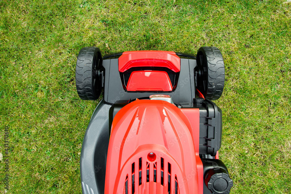 Fototapeta premium lawnmower on grass. Lawn mower across a green lawn. Mow the lawn for a green lawn 