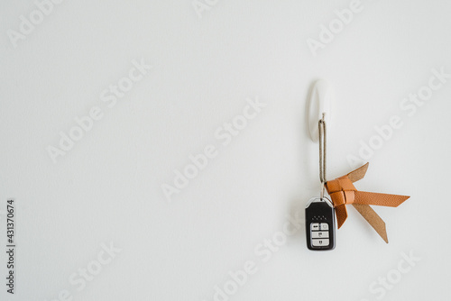 Car key, key chain made from lather to be fish hanging on hook at the whit wall in home or apartment with copy space.