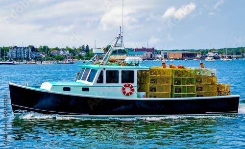 Lobster boat with a full load of yellow lobster traps heading out of the harbor.
