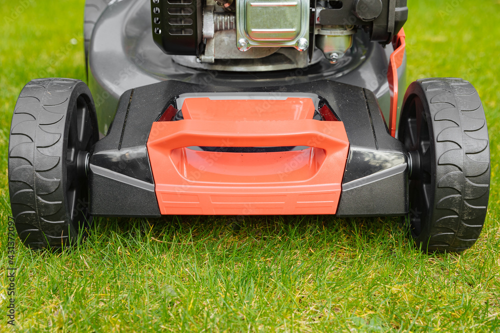 Fototapeta premium Lawn mower across a green lawn. Mow the lawn for a green lawn 