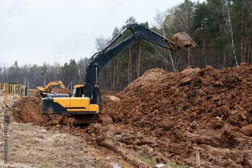 Three excavators in the process of work digs