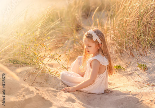 Beautiful little girl with long hair at the beach in summer. Summer vacations with kids concept.