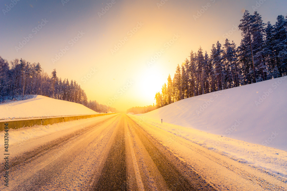 Sunrise on a clear winter morning, empty highways in snow. View from the road. Coniferous forest. Russia, Europe. Beautiful nature.