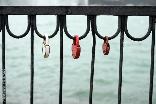 Three love locks hang on the metal wrought-iron fence of the bridge. Copy space.