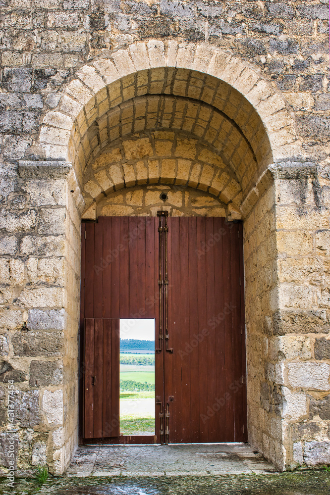 Portón de madera y arco de medio punto en piedra del castillo medieval siglo XIII de Montealegre de Campos, provincia de Valladolid, España