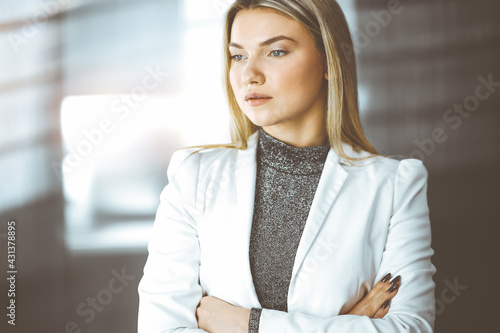 Young blonde business woman or female student standing straight and posing at camera in sunny office Free Download Young blonde business woman or female student standing straight and posing at camera in sunny office - GFXLoad