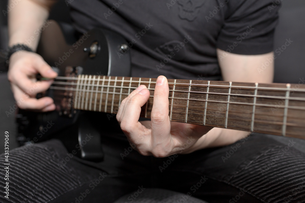 A man playing black electric guitar. Guitar fretboard close-up. Learning to play the guitar. Hand grips chords, A man playing black electric guitar. Guitar fretboard close-up. Learning to play the guitar. Hand grips chords,