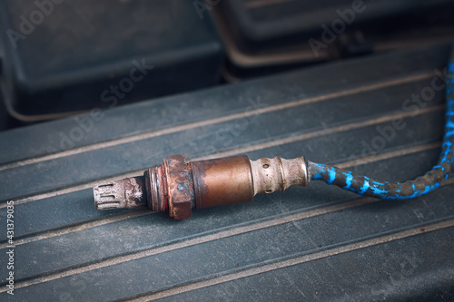 Replace gasoline car oxygen sensor. Old and damaged O2 oxygen, check lambda sensor, close up of engine spare parts. Part of exhaust system of car with combustion engine