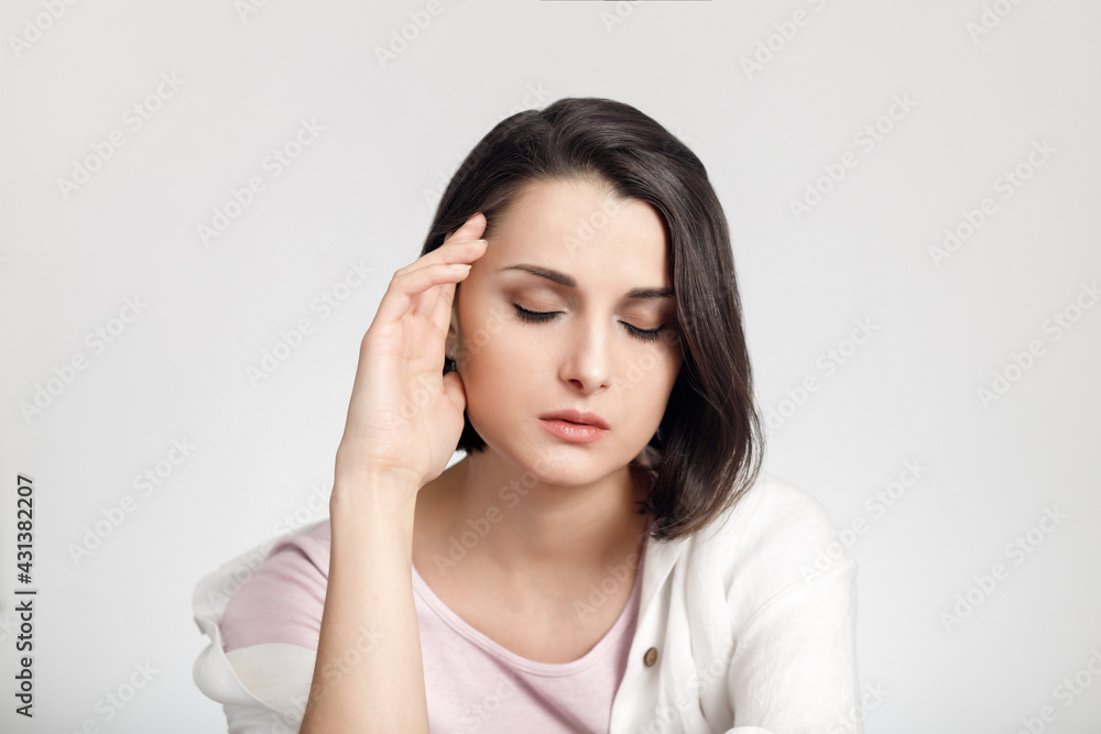 Tired young woman with closed eyes touches her head. Tired young woman with closed eyes touches her head.