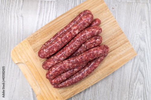 Homemade raw sausages lie on a wooden board