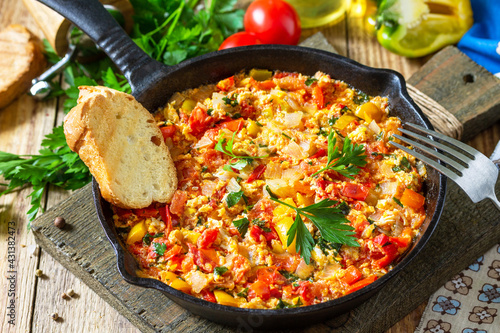 Traditional Turkish dish. Mememen (fried vegetables with scrambled egg) in a cast iron frying pan on a wooden table.