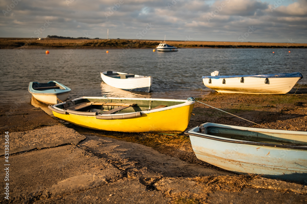 Small pleasure boats beached on the mud at low tide in Wells-Next-The-Sea estuary as the sun starts to set Small pleasure boats beached on the mud at low tide in Wells-Next-The-Sea estuary as the sun starts to set
