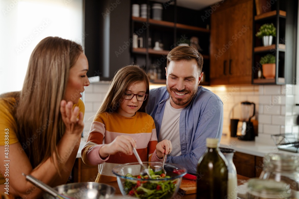 Mom, dad and daughter are cooking on kitchen. Happy family concept.