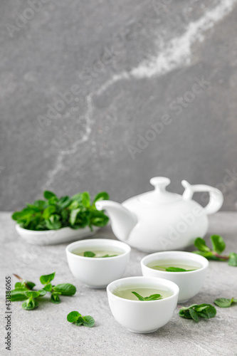Herbal mint tea in small traditional chinese cups and fresh leaves, healthy antioxidant drink