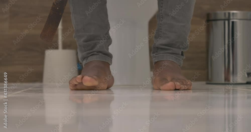 Man sitting on toilet in bathroom. Shot of male's legs dressed in jeans with bare feet. Biological human needs. Healthy bowel movement Man sitting on toilet in bathroom. Shot of male's legs dressed in jeans with bare feet. Biological human needs. Healthy bowel movement
