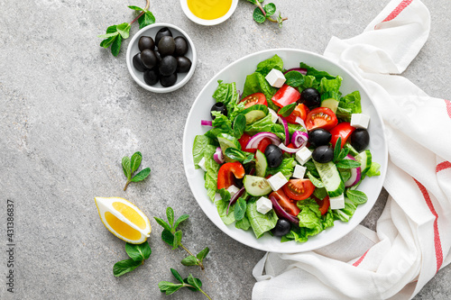 Fresh vegetable greek salad with lettuce, olives and feta cheese, top view