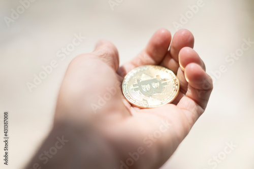 Bitcoin. Hand holding gold coin with BTC symbol. Person investing in virtual assets like cryptocurrency concept background