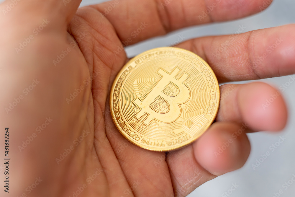 Bitcoin. Hand holding gold BTC coin symbol. Person investing in virtual assets like cryptocurrency concept background Bitcoin. Hand holding gold BTC coin symbol. Person investing in virtual assets like cryptocurrency concept background