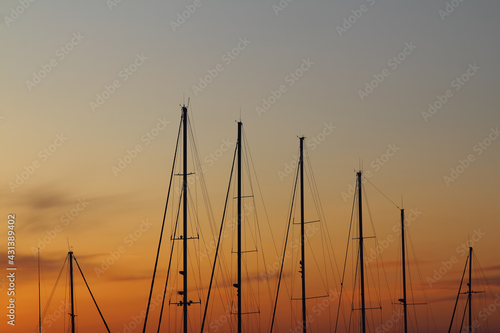 Fiery contrasting clouds in the blue sky, at sunset, through the masts of sailing yachts.