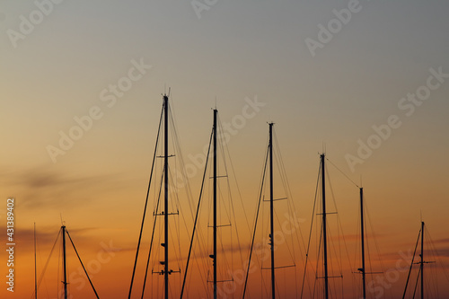 Fiery contrasting clouds in the blue sky  at sunset  through the masts of sailing yachts.