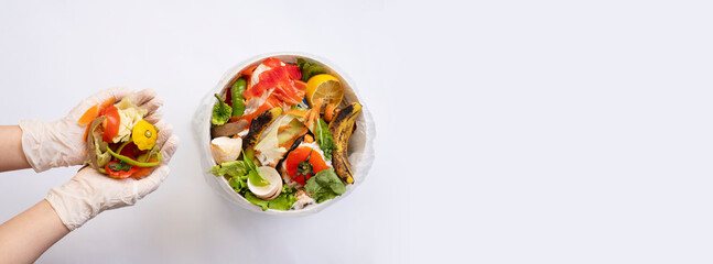 Organic food waste in bowl and in hands on white background top view. Vegetable peelings and food leftovers ready to compost. Environmentally responsible behavior, recycling waste concept. Copy space.