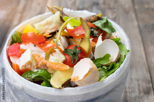 Food leftovers in compost bin on wooden background, compost, vegetable peels concept. Copy space, Sustainable and zero waste