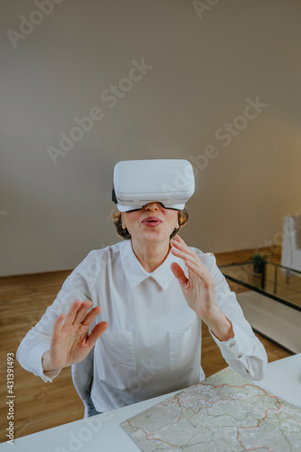 Happy mature woman using VR glasses for travel online