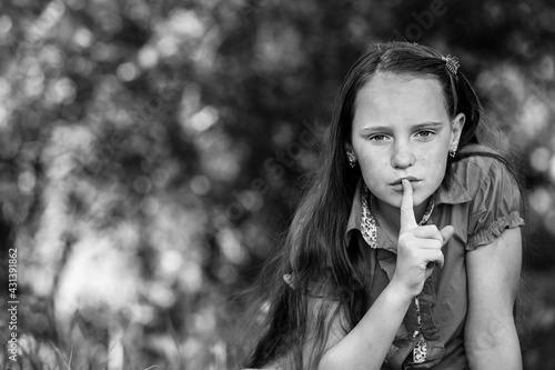Teengirl with her finger over her mouth. Hushing. Black and white photo.