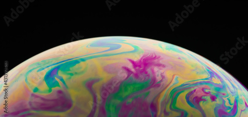 Macro picture of half soap bubble on black ground look like abstract psychedelic color planet in space