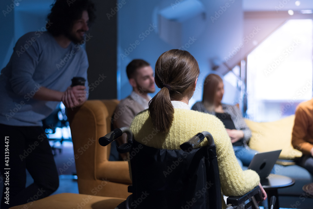 Office workers and person in a wheelchair discussing business moments in a modern office. Disability and business concept Office workers and person in a wheelchair discussing business moments in a modern office. Disability and business concept