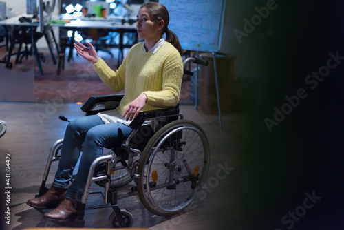 Office workers and person in a wheelchair discussing business moments in a modern office. Disability and business concept