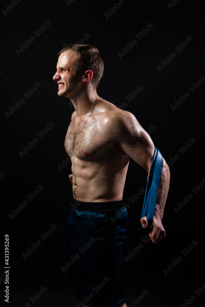 Man on black background keeps dumbbells pumped up in fitness biceps sport, body weight exercise male pectoral. handsome metal, gym fit With a ribbon in hand, the fitness gum is black Man on black background keeps dumbbells pumped up in fitness biceps sport, body weight exercise male pectoral. handsome metal, gym fit With a ribbon in hand, the fitness gum is black