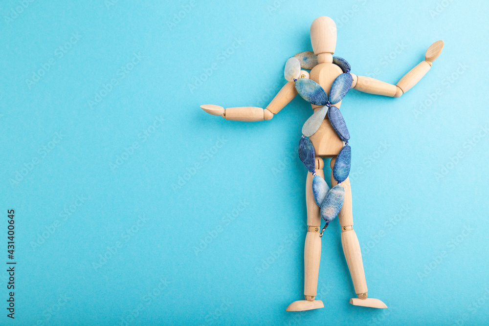 Wooden mannequin with blue agate beads on blue pastel background. copy space. Wooden mannequin with blue agate beads on blue pastel background. copy space.