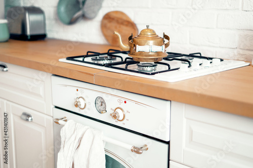 Boil hot water for tea. Copper metal retro teapot vintage stands on a gas stove. Wooden countertop in the kitchen. An antique item in the apartment. Copy space.