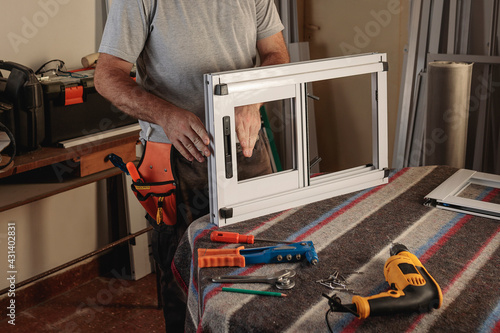 Body part of man working in a carpentry shop. Assembling an aluminum window for a house. Horizontal image.