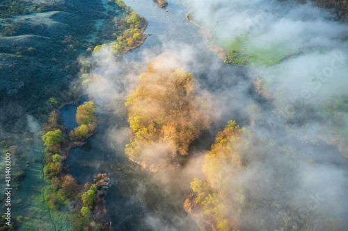 aerial view to island with trees in light between fog on the river © sergejson