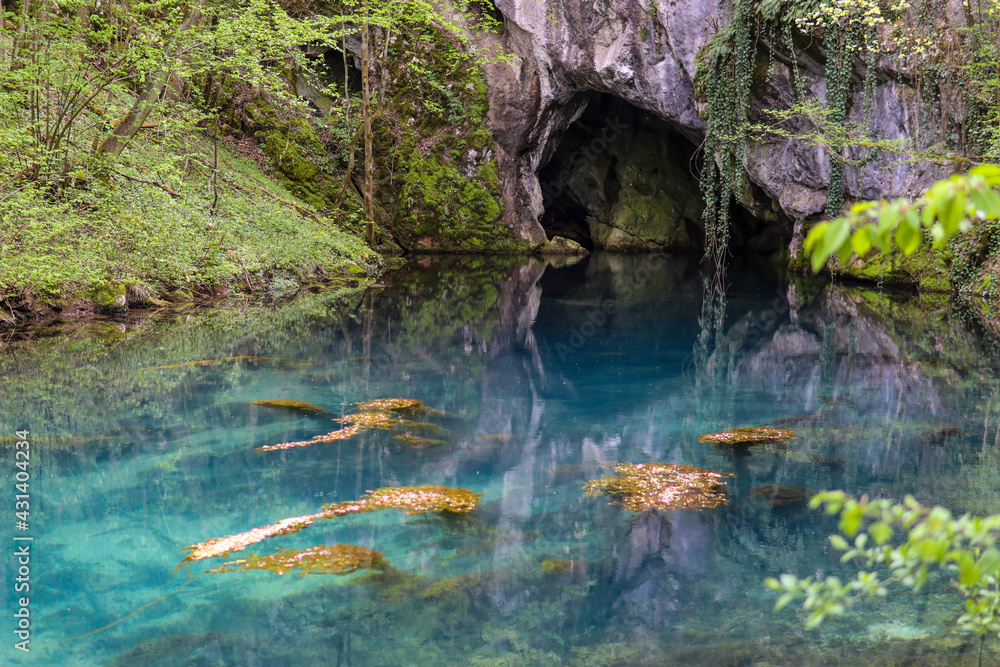 Beautiful turquoise color of the water and cave on Lake Krupajsko in Serbia on a sunny summer day in the forest. National beauty and nature concep Beautiful turquoise color of the water and cave on Lake Krupajsko in Serbia on a sunny summer day in the forest. National beauty and nature concep