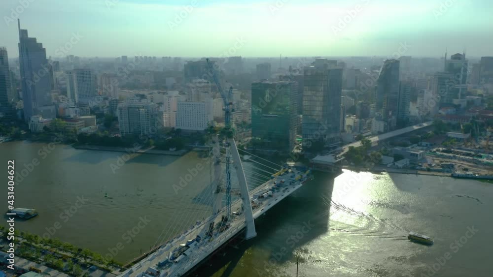 Saigon river waterfront with long afternoon shadows from the Ho Chi Minh City skyline, a symbol of modern Vietnam. Orbit of Thu Thiem Two Bridge under construction Saigon river waterfront with long afternoon shadows from the Ho Chi Minh City skyline, a symbol of modern Vietnam. Orbit of Thu Thiem Two Bridge under construction