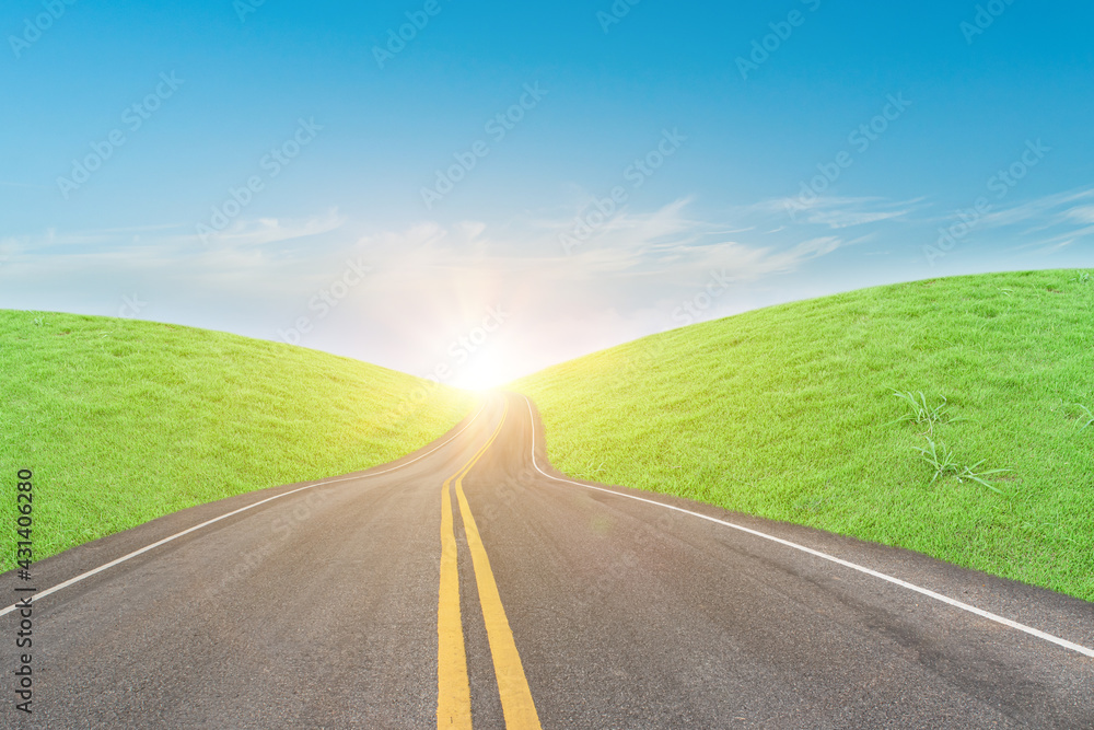 Asphalt road and green grass field in countryside on sunny day.